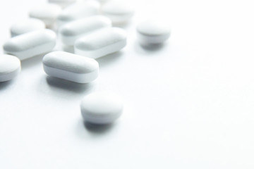 White capsules isolated on white background, copyspace for text, selective focus, top view. Pain meds, health, pills for the treatment of the concept of drug abuse