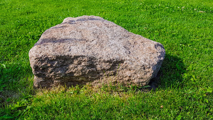A stone on green grass can be a decoration for any lawn.