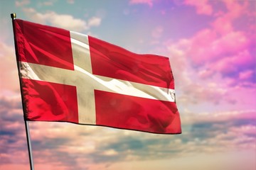 Fluttering Denmark flag on colorful cloudy sky background. Prosperity concept.