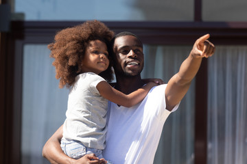 African father holds daughter on hands showing something interesting