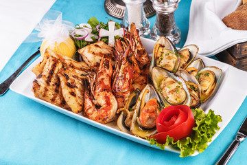 European cuisine, Mediterranean dish. Plate with assorted sea grill. Fried fish, king prawns with lemon, mussels with oyster sauce, colmar rings, crab meat