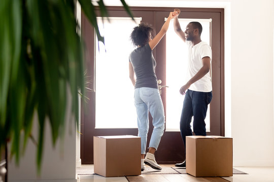 African millennial couple dancing at hallway on moving day - Powered by Adobe