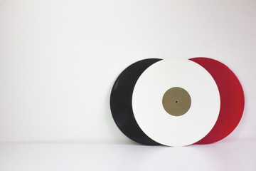 Three vinyls, black, red and white, on white background, with white space.