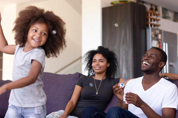 Family having fun with kid and soap bubbles at home