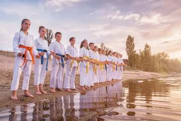 group of kids training karate martial arts on sunset beach