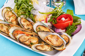 European cuisine, Mediterranean dish. Plate of assorted mussels and oysters cooked with spices, onions, herbs, tomatoarmi and lemons