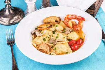European cuisine, Italian cuisine, Mediterranean dish. Raviolli with fish meat, squid, herbs, tomatoes and shrimps