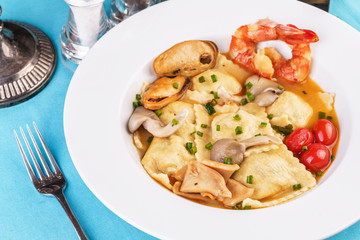 European cuisine, Italian cuisine, Mediterranean dish. Raviolli with fish meat, squid, herbs, tomatoes and shrimps