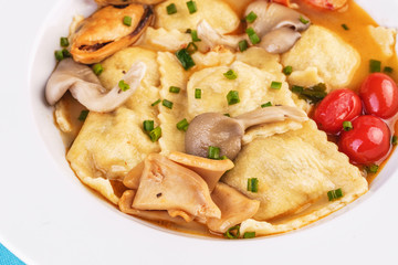 European cuisine, Italian cuisine, Mediterranean dish. Raviolli with fish meat, squid, herbs, tomatoes and shrimps