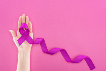 cropped view of woman holding long purple ribbon isolated on pink - obrazy, fototapety, plakaty
