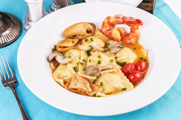 European cuisine, Italian cuisine, Mediterranean dish. Raviolli with fish meat, squid, herbs, tomatoes and shrimps