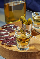 Mezcal in a glass of hot pepper on a steel skewer standing on the oak surface.