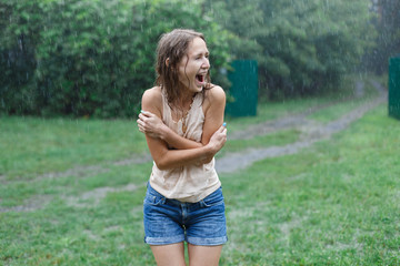 Happy smiling woman under summer rain.emotional girl wet in the rain without umbrella.woman walk in...