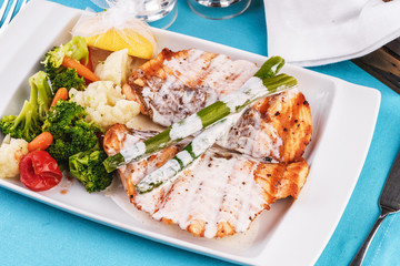 European cuisine, Mediterranean dish. Grilled atrantik salmon steak with cream sauce, served with vegetables and salad