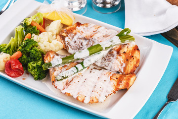 European cuisine, Mediterranean dish. Grilled atrantik salmon steak with cream sauce, served with vegetables and salad