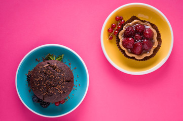 Strawberries tart dessert and chocolate muffin with pink background. Top view