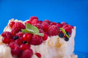  meringue pie with raspberries, blueberries and mint, on a blue background
