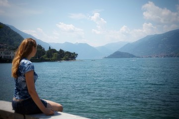 Fototapeta na wymiar Girl sitting and looking on the Lake Como of Bellagio.
