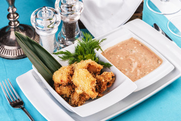 European cuisine, Mediterranean dish. Fried sea fish nuggets in batter with mustard-cream sauce