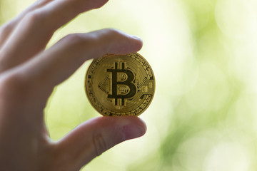 Fototapeta na wymiar Bitcoin coin in hand on blurred background. Closeup front view