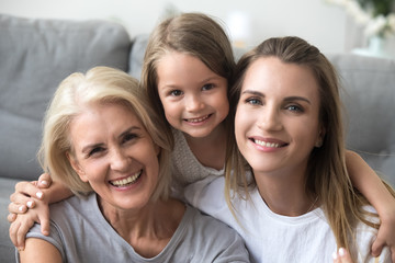 Happy laughing granddaughter mother and grandmother looking at camera