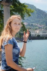 Fototapeta premium A girl with her eyes closed with her hand cleans her hair on the promenade of Bellagio.