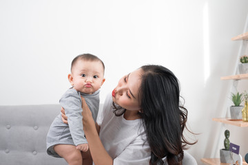 Young mother with her one years old little son dressed in pajamas are relaxing and playing in the living room at the weekend together, lazy morning, warm and cozy scene. Selective focus.