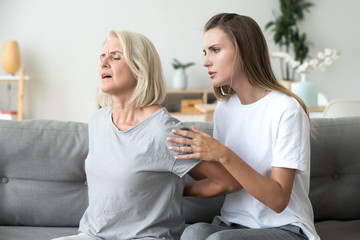 Mother suffering from back pain daughter feeling worry