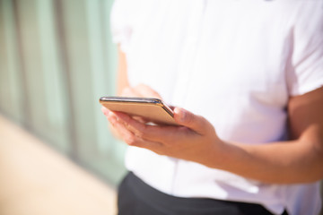 Cropped shot of woman using mobile phone. Close-up partial view of businesswoman using smartphone, selective focus. Technology concept