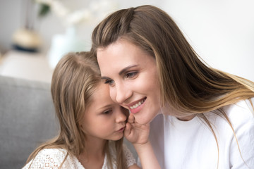 Daughter whispering to moms ear a secret