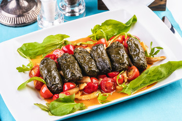 Uzbek cuisine, oriental cuisine. Dolma - Leaves of grapes, boiled rolls with meat, beef and rice. Served with vegetables - tomatoes, peppers, cucumbers and onions