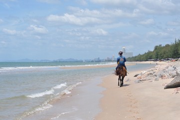 People riding on horse back at the cha am beach in Thailand.