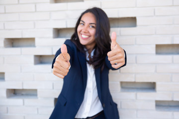 Happy businesswoman showing thumbs up. Beautiful cheerful young businesswoman showing thumbs up and smiling at camera. Gesture concept