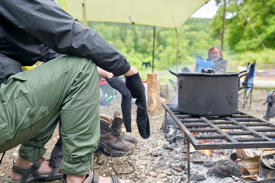 Tourist Dries Wet Socks Sitting By The Fire. Easy Defocus