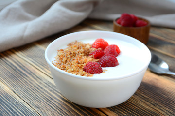 Delicious yogurt with granola and fresh raspberry in a bowl on wooden background Healthy food concept 