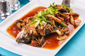 Seafood, Mediterranean cuisine, European dish. Fish stewed in tomato sauce with onion rings, mushrooms, herbs and vegetables. Caucasian national cuisine