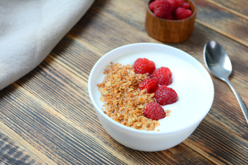 Delicious yogurt with granola and fresh raspberry in a bowl on wooden background Healthy food concept 