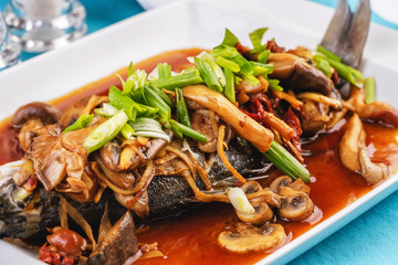 Seafood, Mediterranean cuisine, European dish. Fish stewed in tomato sauce with onion rings, mushrooms, herbs and vegetables. Caucasian national cuisine