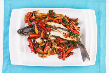 Seafood, Mediterranean cuisine, European dish. Whole fish baked with tomatoes with onion rings, red and green peppers, chili peppers, greens and vegetables. Caucasian national cuisine