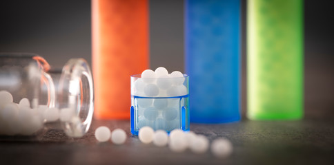 Modern Color homeopathic pills in plastic container on black background