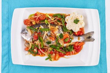 Seafood, Mediterranean cuisine. Baked sea fish with mushrooms, herbs, carrots, millers, cilantro, corn and onions. Caucasian national cuisine