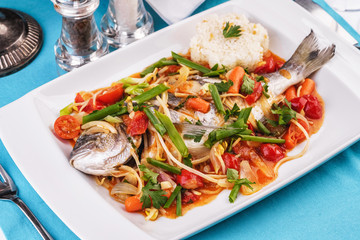 Seafood, Mediterranean cuisine. Baked sea fish with mushrooms, herbs, carrots, millers, cilantro, corn and onions. Caucasian national cuisine