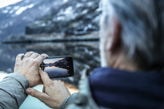 homme mature prenant une photo des fjords de Norvège