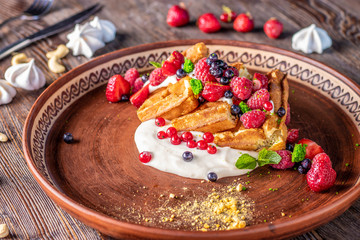 Homemade waffles with berry salsa and cream cheese in a plate on a wooden table, horizontal photo
