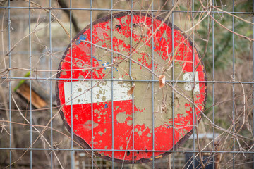 dirty german no entry traffic sign, behind a metal fence