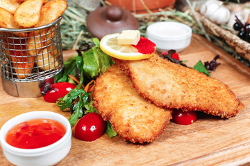 Fish crocheted in batter, with potatoes rustic, with greens, cherry tomatoes, cucumbers, tomato and cream sauces