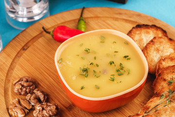 Mediterranean dish, European cuisine. Fish and cream cheese soup with herbs, garlic bread, red and green chili peppers, thyme and walnuts