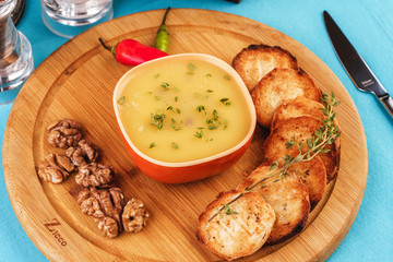 Mediterranean dish, European cuisine. Fish and cream cheese soup with herbs, garlic bread, red and green chili peppers, thyme and walnuts