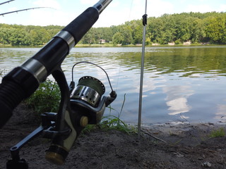Fishing on the forest lake. Male hands twist the spinning reel while fishing. Spinning reel...