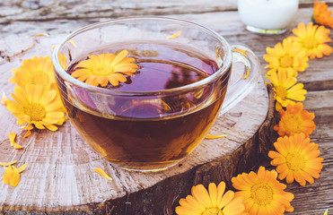 Herbal tea from calendula flowers in a transparent glass mug. Extract of tincture of calendula in the cup.